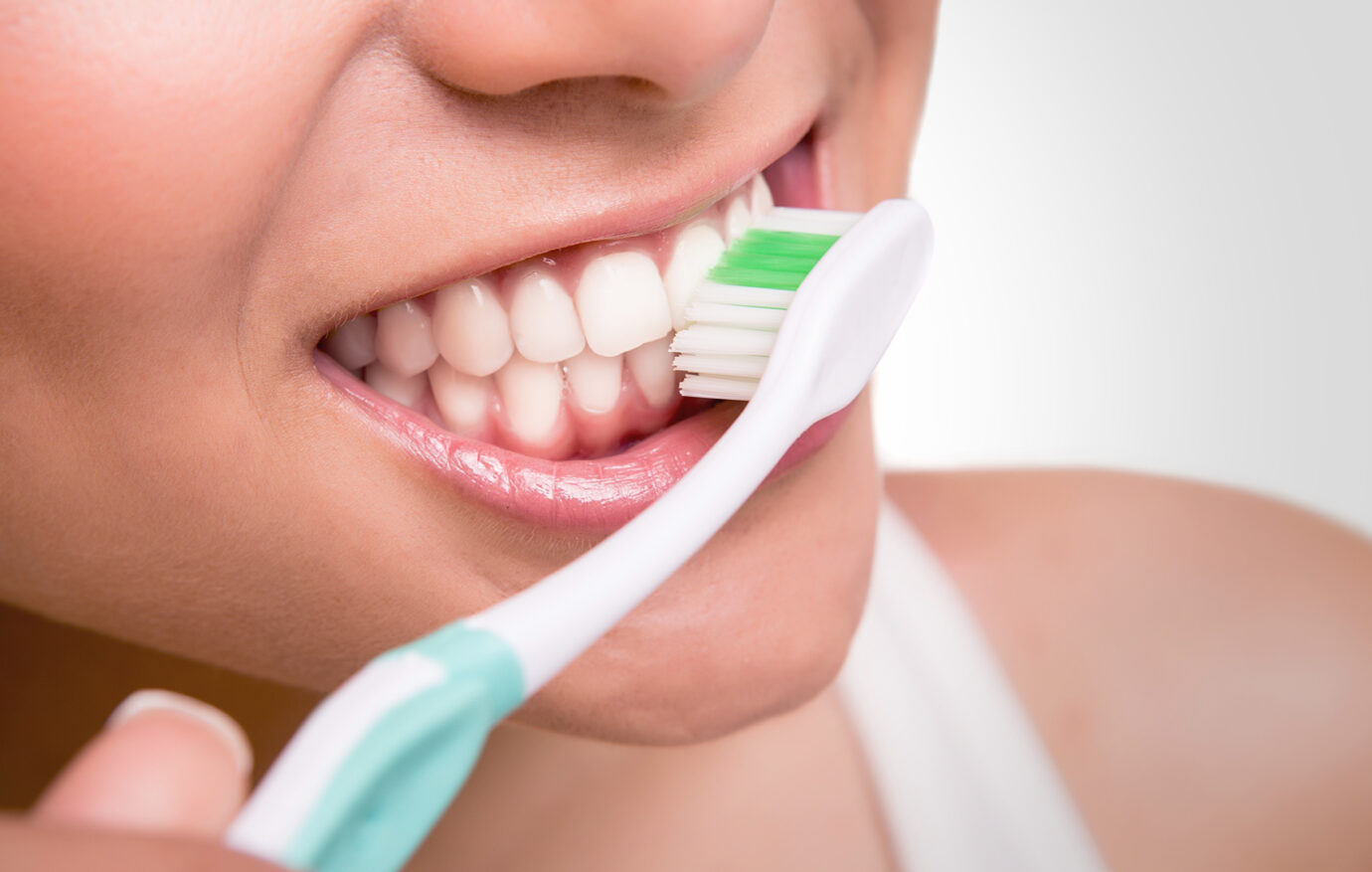 Smiling young woman with healthy teeth holding a tooth brush